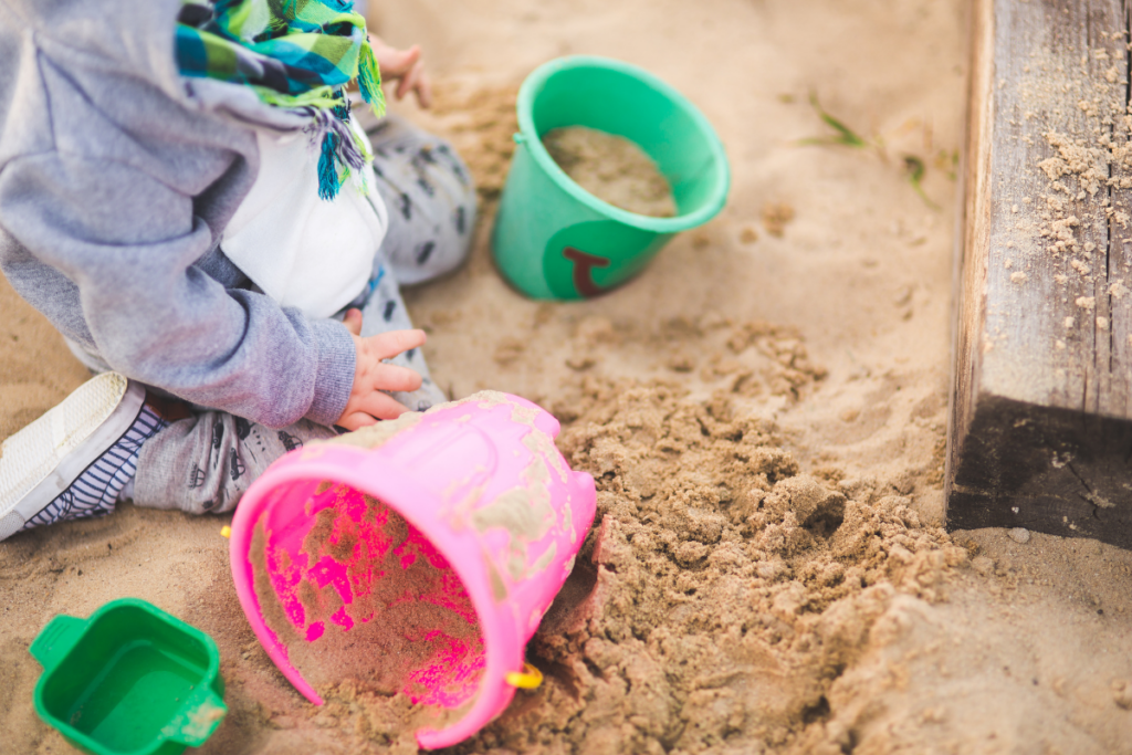 Kind mit Eimerchen im Sandkasten